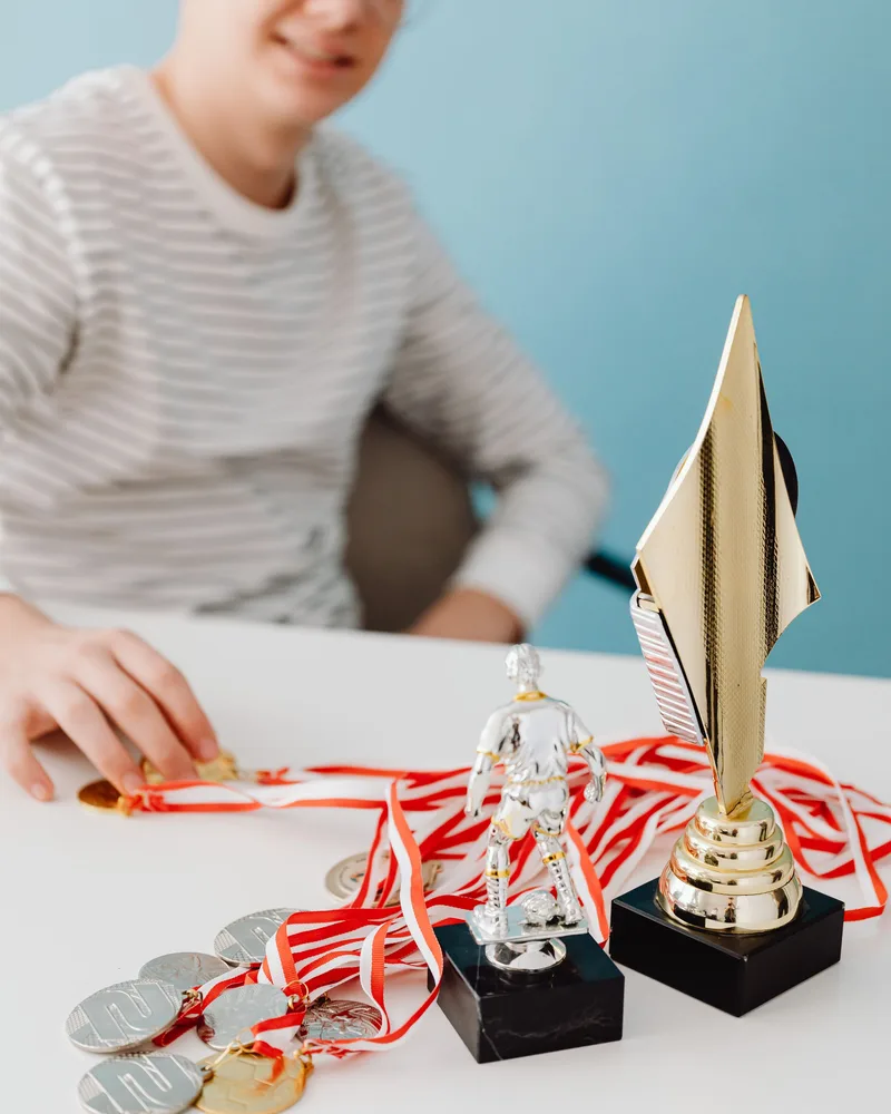 Student with award medals and trophies on a table — 3DSchool.eu